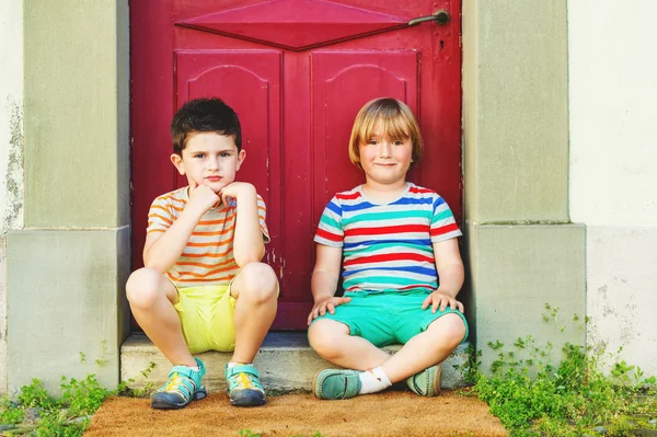 Gruppo di due simpatici ragazzini che giocano insieme all'aperto, indossando magliette colorate, pantaloncini e scarpe, moda estiva per bambini . — Foto Stock