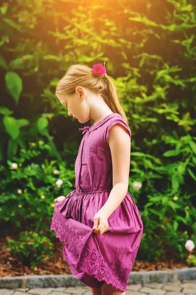 Kid girl playing in the park on a nice and sunny summer day, wearing purple dress — Stock Photo, Image