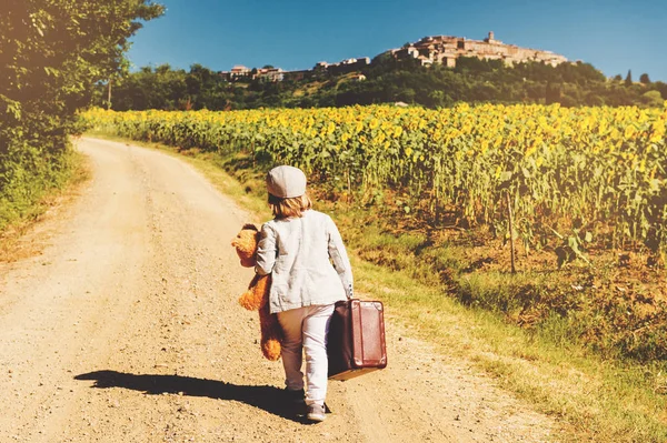 Açık portre kırsal, holding eski küçük bavul ve oyuncak ayı oyuncak, arkadan görünüm yolda yürürken küçük komik bir çocuk. Toskana, İtalya alınan görüntü — Stok fotoğraf