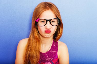 Stüdyo çekim genç varoluş 9-10 yıl yaşlı kız gözlük, mavi mor arka plan karşı ayakta giyiyor