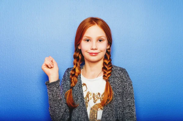 Estudio de toma de bastante preadolescente niña pelirroja de 9-10 años, usando cárdigan gris, de pie sobre fondo azul púrpura — Foto de Stock