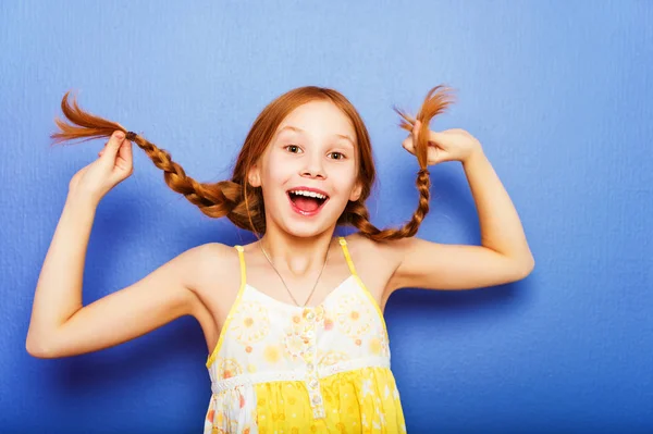 Estúdio tiro de jovem pré-adolescente 9-10 anos menina ruiva vestindo top amarelo, de pé contra o fundo roxo azul — Fotografia de Stock