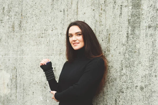 Outdoor portrait of young 35 year old woman with long dark hair, wearing black turtle neck dress — Stock Photo, Image