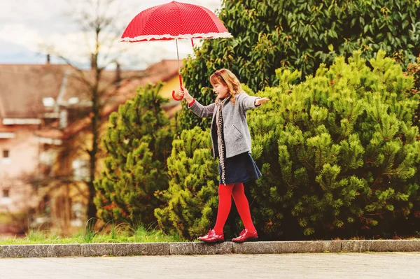 Funny little girl playing outdoors with big red polkadot umbrella — Stock Photo, Image