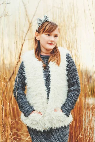 Ritratto all'aperto di carina ragazza di 8-9 anni che indossa pullover grigio e gilet in eco-pelliccia bianca — Foto Stock