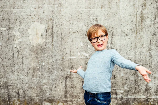 Ritratto all'aperto di un bambino carino che indossa occhiali, pullover azzurro e jeans in denim — Foto Stock