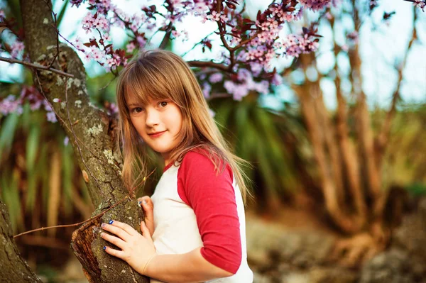 Little girl in the spring garden at sunset — Stock Photo, Image