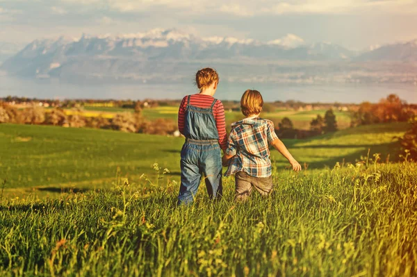 Dvě děti, malý bratr a starší sestra, hrát spolu venku v oblastech Švýcarska s zobrazit na Ženevské jezero a francouzské hory Haute-Savoie. Snímek pořízený v Lausanne oblasti, Kanton Vaud, Švýcarsko — Stock fotografie
