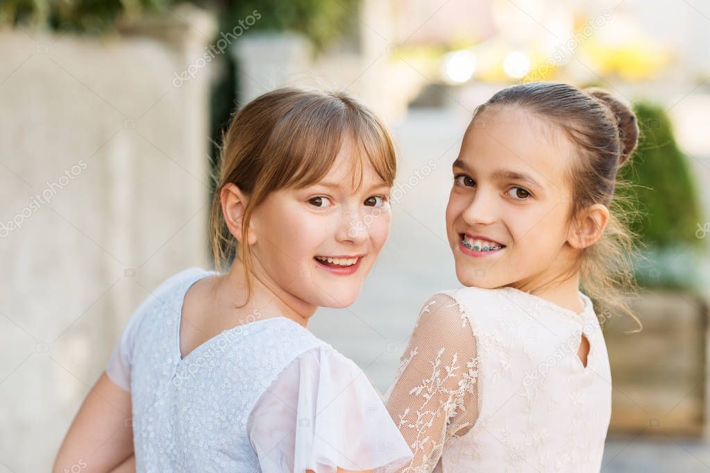 Outdoor portrait of two sweet kid girls wearing party dresses