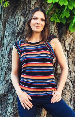 Çizgili gömlek büyük ağaç karşı ayakta kameraya bakarak waring genç güzel esmer kadın portresi