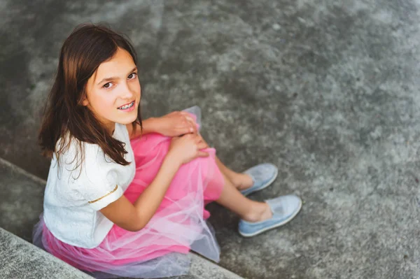 Preteen girl s zuby rovnátka nosit krásné šaty, zatímco sedí na schodech, pohled shora — Stock fotografie