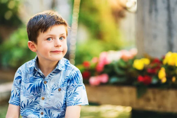 Открытый летний портрет очаровательного мальчика, отдыхающего на улице рядом с фонтаном в очень жаркий солнечный день, в голубой рубашке — стоковое фото