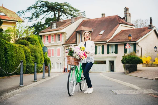 Piękne blond kobieta stojąc obok miętowy kolor rower z Duży kolorowy bukiet kwiaty w koszyku — Zdjęcie stockowe