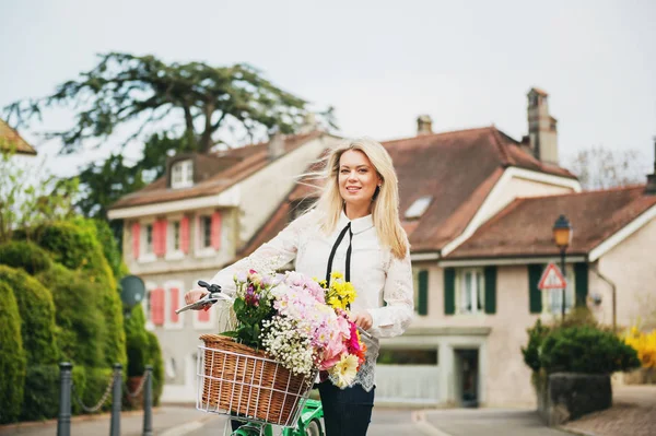 Красивая блондинка стоит рядом с мятным велосипедом с большим красочным букетом цветов в корзине — стоковое фото