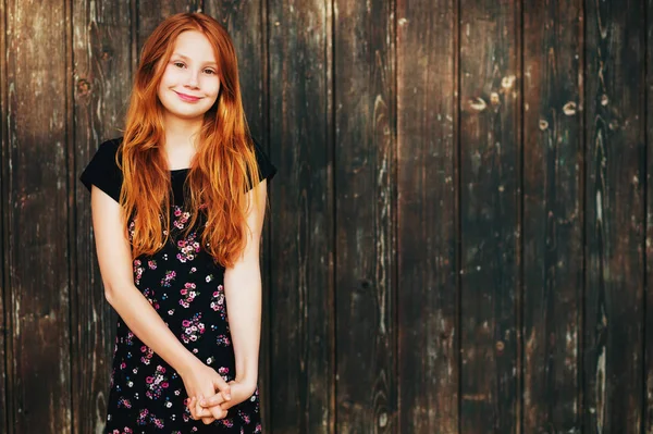 Outdoor fashion portrait of happy red-haired girl, posing against old wooden background — Stock Photo, Image