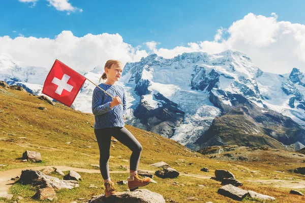 Милая маленькая девочка с флагом Швейцарии, стоящая перед ледником Горнерграт, Швейцария — стоковое фото