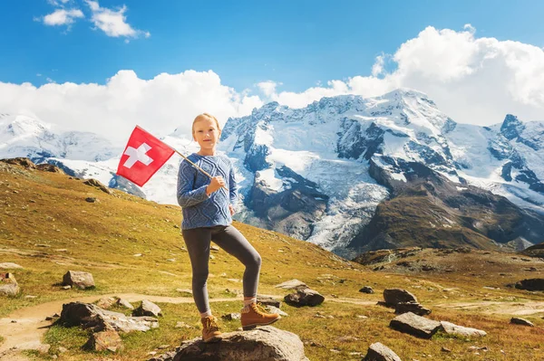 Söt liten flicka innehav schweizisk flagga, står framför Gornergrat glaciär, Schweiz — Stockfoto