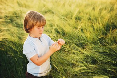 Yaz aylarında gün batımı buğday alanında oynayan küçük tatlı çocuğa