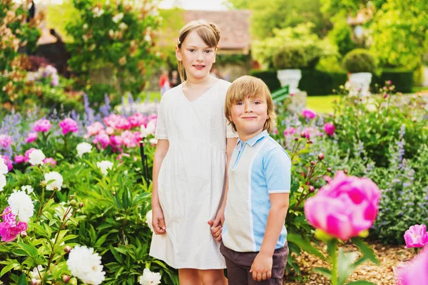 Модные дети позируют в красивом саду, в винтажном стиле одежды. Лето цветет лавандой и пионами — стоковое фото