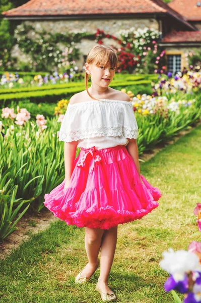 Utomhus porträtt av bedårande liten flicka som leker i en vacker blomma park på en fin sommardag. Mode barn flicka klädd i vit blus och ljusa rosa tutu kjol — Stockfoto