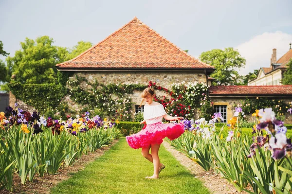 Słodkie dziecko dziewczynka tańczy w pięknym ogrodzie kwiat na ładny słoneczny letni dzień, sobie jasne różowe tutu spódnica — Zdjęcie stockowe