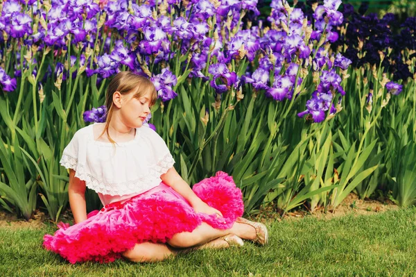 Słodkie dziewczyny trochę gry w Iris flower garden w piękny letni dzień, na sobie białą koszulę i spódnicę jasne różowe tutu — Zdjęcie stockowe
