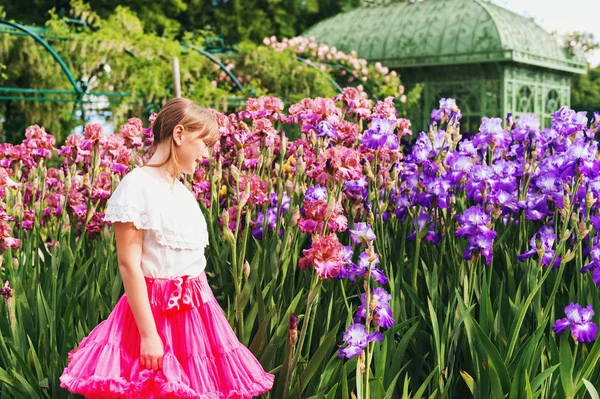 Słodkie dziewczyny trochę gry w Iris flower garden w piękny letni dzień, na sobie białą koszulę i spódnicę jasne różowe tutu — Zdjęcie stockowe