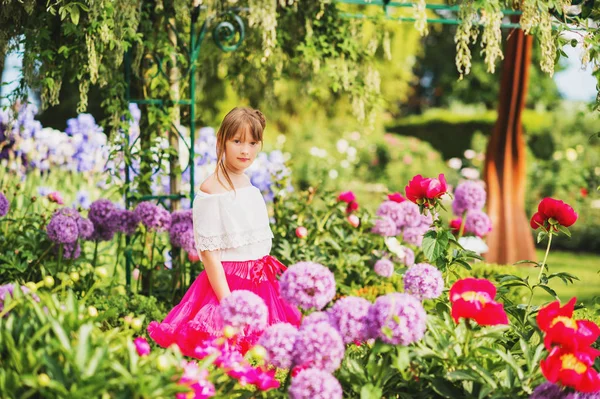 Ganska lite 9-10 år gammal flicka spelar i vacker trädgård, klädd i ljusa rosa tutu kjol — Stockfoto
