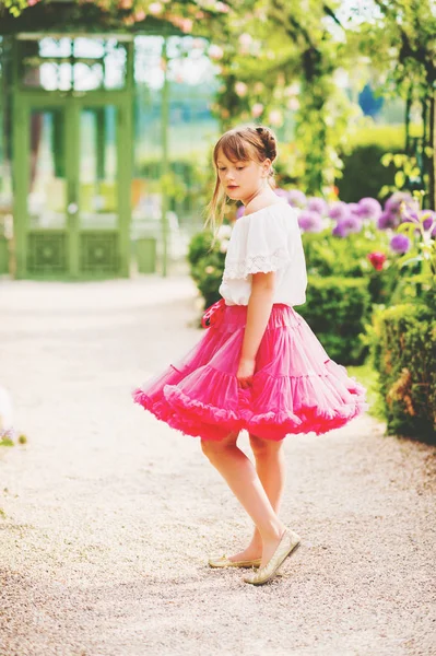 Szép kis 9-10 év régi lány gyönyörű kertben játszik, fárasztó szoknya világos rózsaszín tutu — Stock Fotó