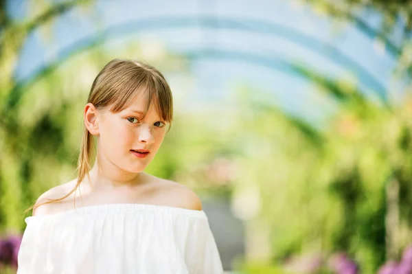 Utomhus närbild porträtt av en söt 9-10 år gammal liten flicka i en vacker park med en båge — Stockfoto