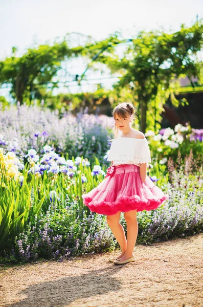 Linda menina de 9-10 anos de idade jogando em belo jardim, vestindo saia de tutu rosa brilhante — Fotografia de Stock