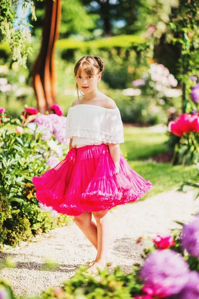 Dziewczyna dość mało 9-10 roku grając w pięknym ogrodzie, noszenie spódnicy jasne różowe tutu — Zdjęcie stockowe
