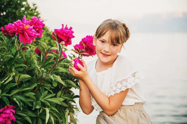 Retrato ao ar livre de adorável menina posando com peônias rosa brilhantes pelo lago Genebra, Suíça — Fotografia de Stock