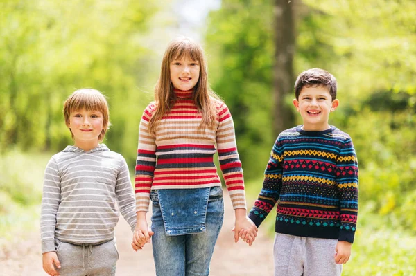 Skupina tří šťastné dětství v jarní Les, dva chlapci a jedna dívka spolu hrají venku, nošení roláků — Stock fotografie