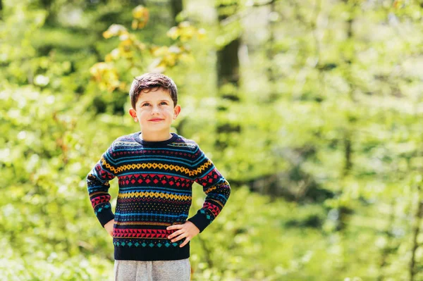 Lindo niño disfrutando del bosque fresco de primavera, usando un jersey cálido y colorido — Foto de Stock