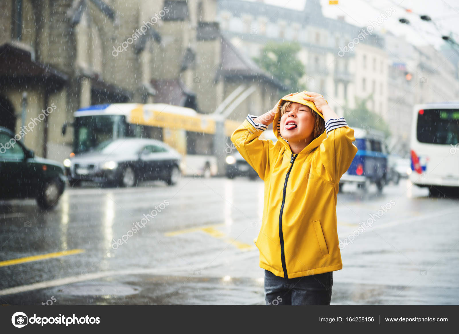 Cute little boy playing under the rain in a city, wearing bright yellow