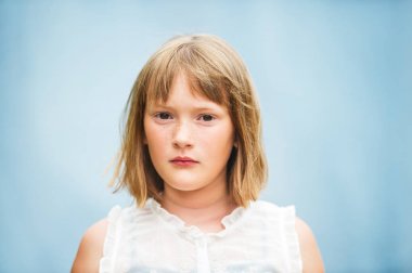 Kısa bob saç kesimi ayakta mavi arka plan ile sevimli küçük kız portresi kapatın