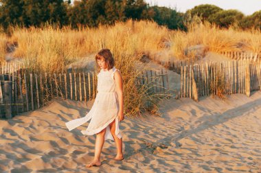 Kum plajı üzerinde günbatımında deniz kenarında dans güzel çocuk kız. Varoluş çocuk Güney Fransa yaz tatilinin tadını çıkarıyor