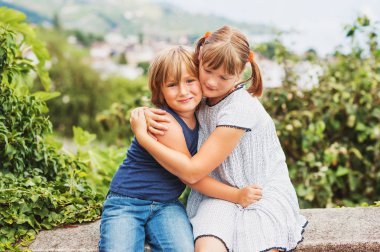 Kardeşler birbirlerini, kardeşi ve kız kardeşi birlikte oynayan sarılma mutlu küçük çocuklar sever