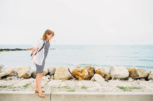 Niña disfrutando de vacaciones de verano junto al mar, vistiendo vestido náutico a rayas y mochila. Imagen tomada en Saintes-Maries-de-la-Mer, capital de Camargue, sur de Francia — Foto de Stock