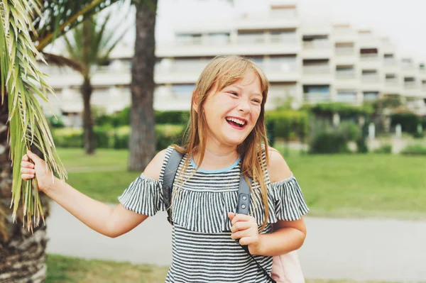 Glücklich lachende junge Mädchen genießen Sommerferien. Ein 10-jähriges Kind trägt T-Shirt und Rucksack mit kalter Schulter. Reisen mit Kindern — Stockfoto