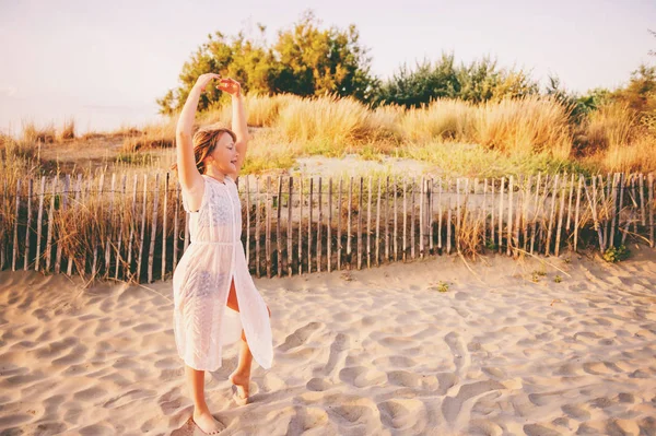 Красивая девочка танцует на песчаном пляже у моря на закате. Подросток отдыхает летом на юге Франции — стоковое фото