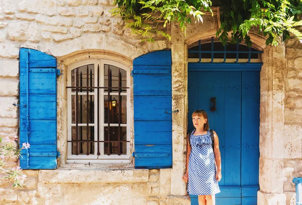 Bella turista bambina per le strade della Provenza, indossando abito blu gingham, occhiali da sole e zaino. Viaggia con il concetto di bambini. Immagine scattata ad Arles, Francia — Foto Stock