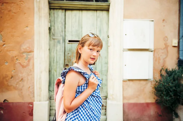 Bella turista bambina per le strade della Provenza, indossando abito blu gingham, occhiali da sole e zaino. Viaggia con il concetto di bambini. Immagine scattata ad Arles, Francia — Foto Stock