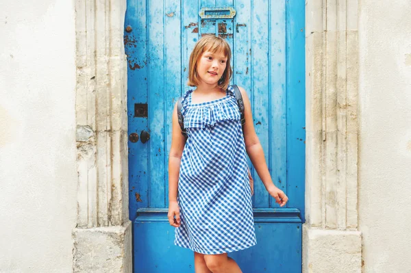 Bella turista bambina per le strade della Provenza, indossando abito blu gingham e zaino. Viaggia con il concetto di bambini. Immagine scattata ad Arles, Francia — Foto Stock