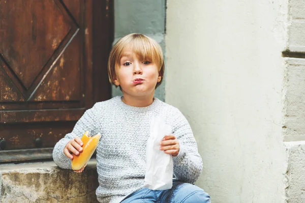 Garoto adorável comendo sanduíche de salame lá fora — Fotografia de Stock