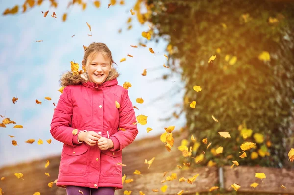 Grappige meisje spelen in herfst park, het dragen van heldere rode parka jas — Stockfoto