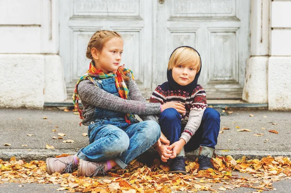 Retrato de otoño de 2 niños adorables en una ciudad, con pulóveres cálidos y vaqueros —  Fotos de Stock