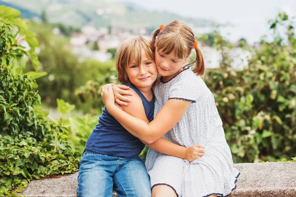 Kardeşler birbirlerini, kardeşi ve kız kardeşi birlikte oynayan sarılma mutlu küçük çocuklar sever