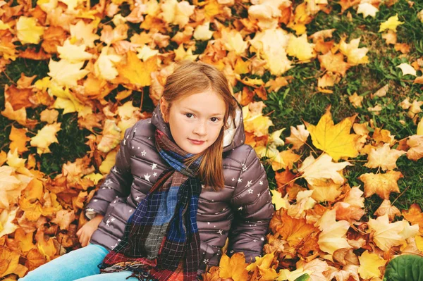 Herfst portret van een schattig klein meisje van 8 jaar oud, spelen met gele bladeren in het park, bovenaanzicht — Stockfoto